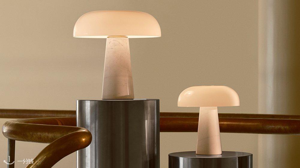 Deux lampes de table cylindriques avec des abat-jours lisses et translucides de couleur blanc chaud. Les matériaux de base sont en pierre et en métal ; les formes sont arrondies, au design moderne.