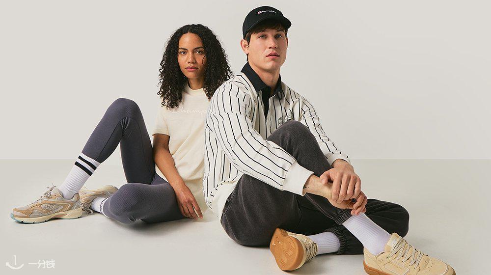 Deux personnes sont assises sur un fond clair. La femme porte un T-shirt beige, des leggings gris avec des rayures, et des baskets. L'homme porte une veste rayée, un pantalon gris, et des baskets beiges.